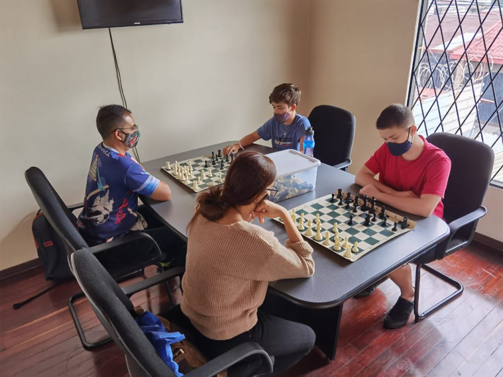 4 personas en una mesa jugando ajedrez